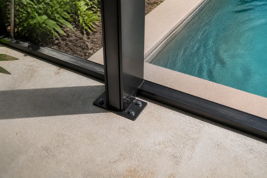 The base of a screen enclosure frame bolted to a pool deck