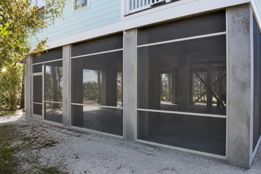 Insect screening panels set between the piles beneath an elevated coastal house