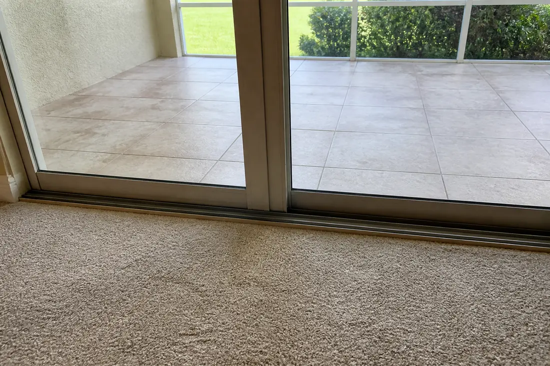 Closed sliding glass doors in the rear wall of a house with a sunroom floor beyond