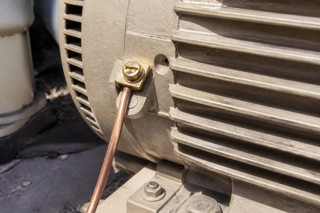 A bonding lug on a pool pump motor with a bare copper conductor clamped under it
