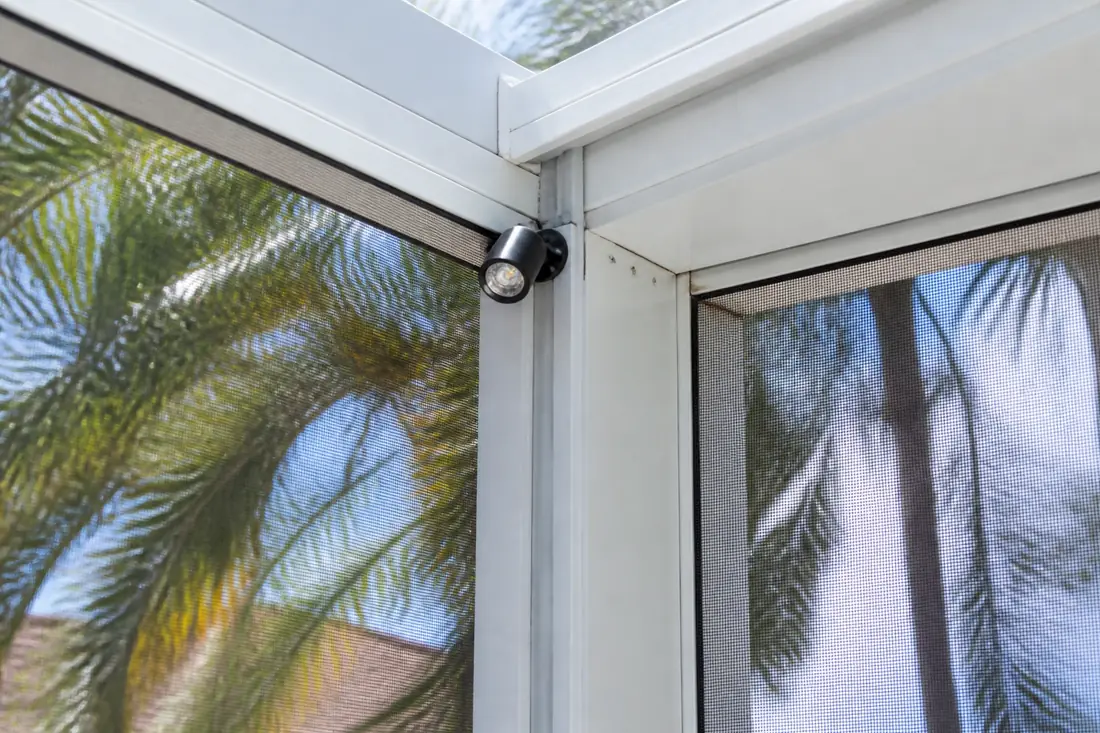A light fixture fixed to the aluminum frame member of a pool enclosure