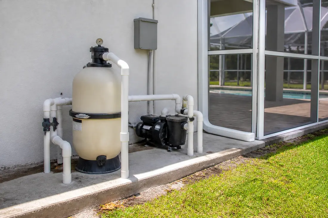 Pool equipment on a slab outside the corner of a screened pool enclosure in Southwest Florida